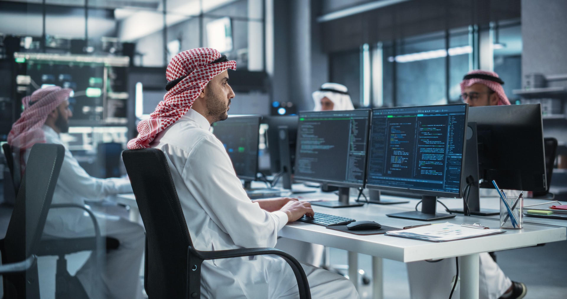 Team of Talented Young Arab Professionals Working in a Technological Research and Development Agency. Computer Screens with Software Code and Technical Neural Network Diagrams in Muslim Office